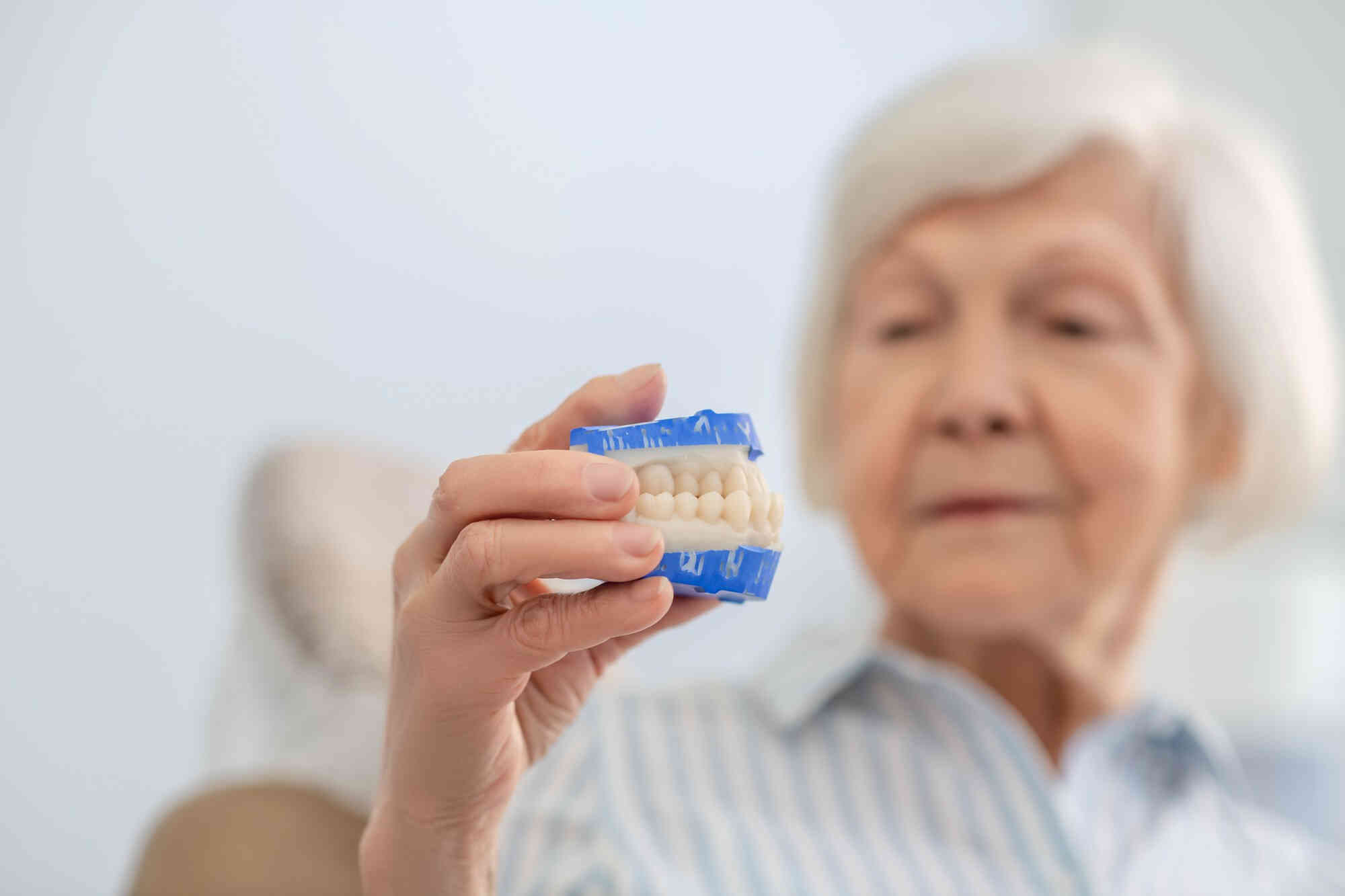 Starsza kobieta zapoznaje się z modelem - odlewem do protezy zębowej